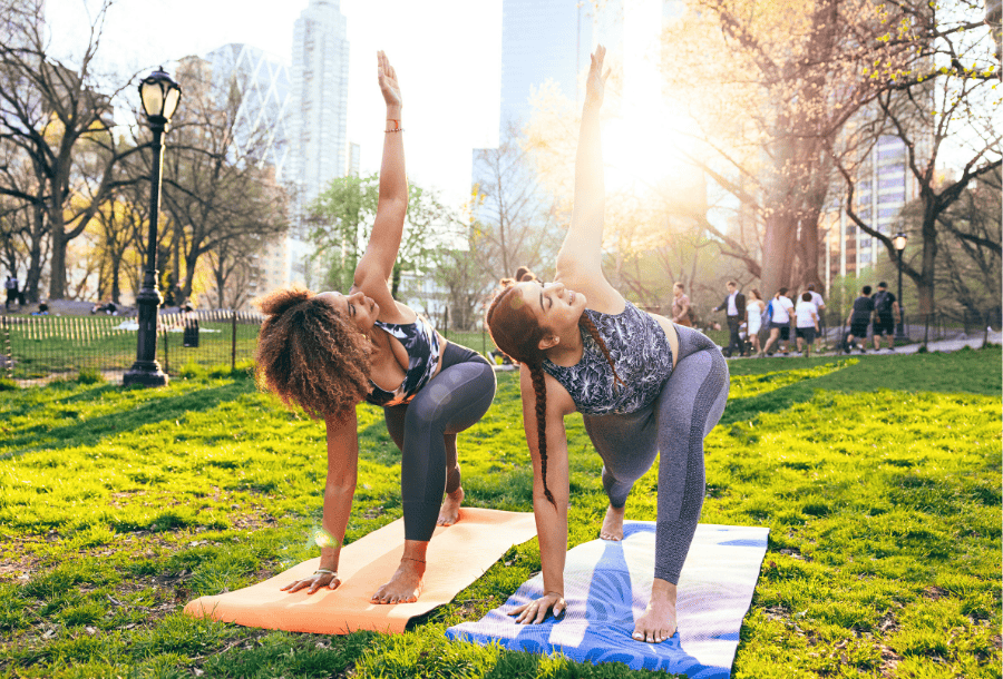 Two friends doing yoga. They are celebrating both National Best Friends Day and the Academy Bank refer-a-friend program.
