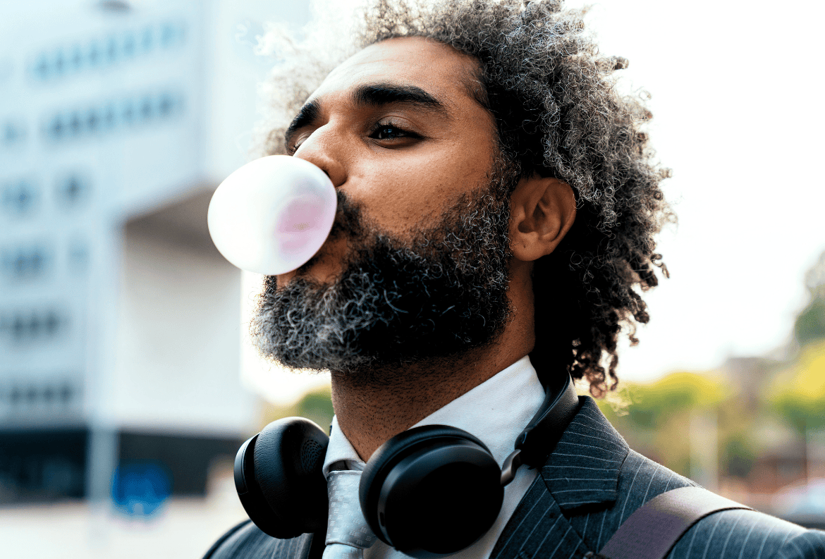 Man blowing bubble gum, feeling carefree and financially secure from having the best money market account.