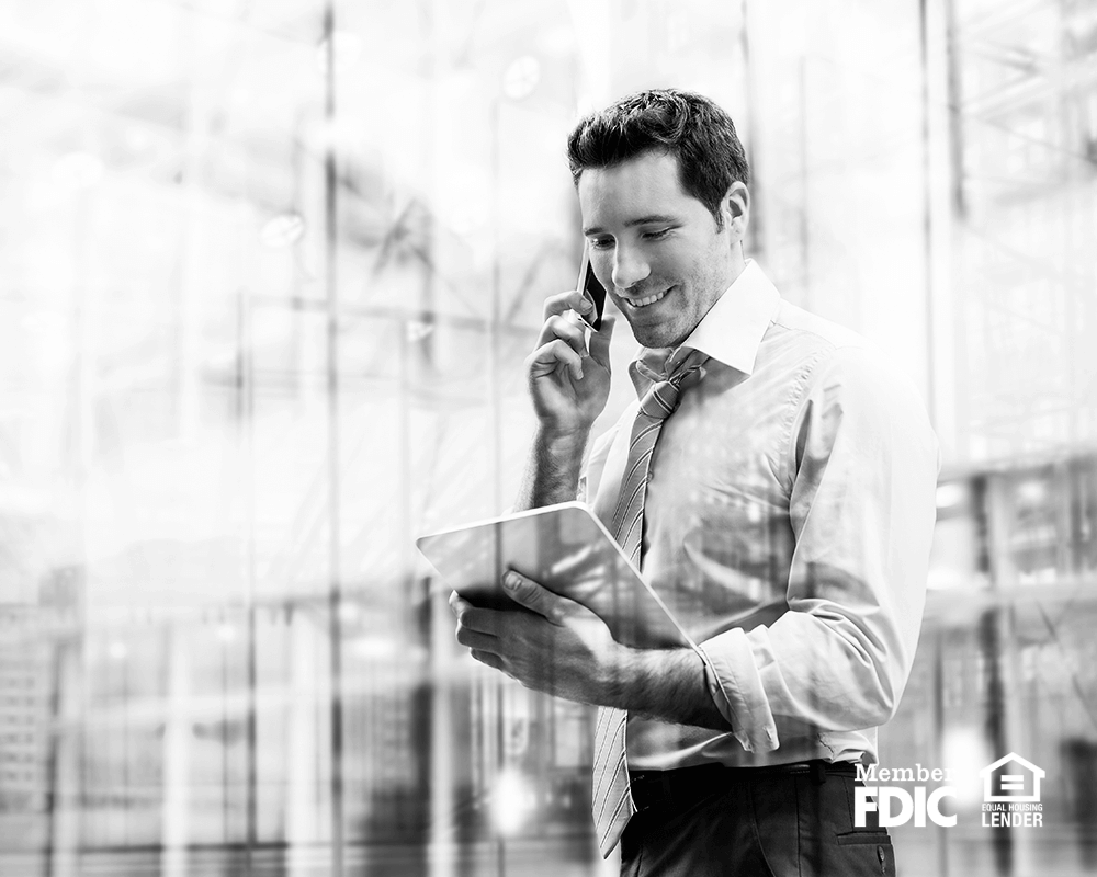 a business man talks on the phone while checking his notes about Academy Bank's treasury management services