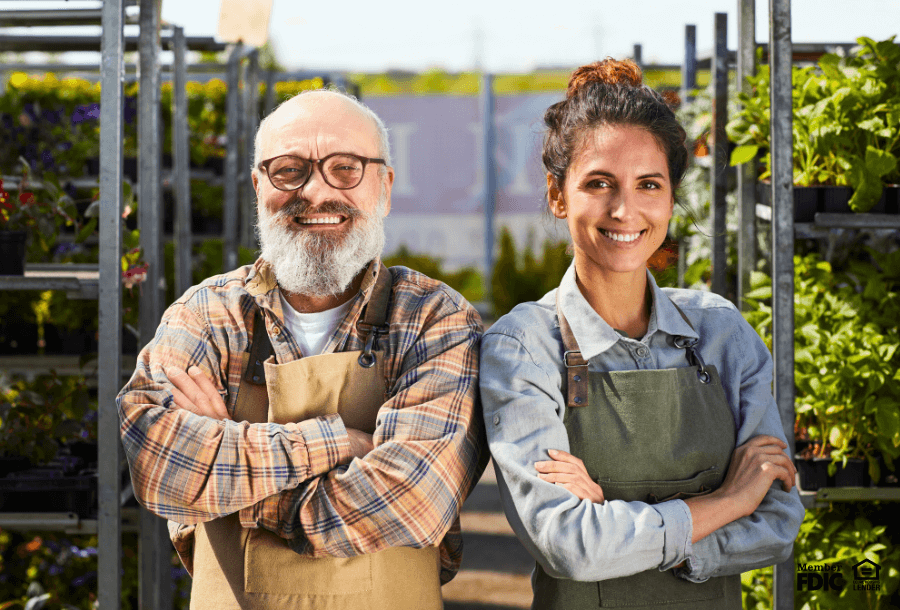 Two horticulture professionals pose with racks of plants