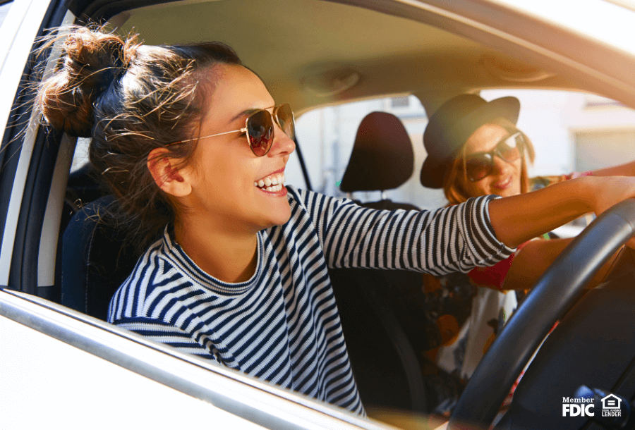 two women driving their car with the windows down. 