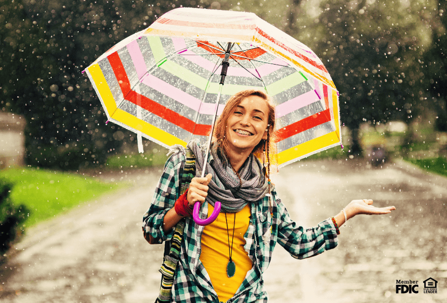 a woman enjoys walking outside in the rain with a striped umbrella