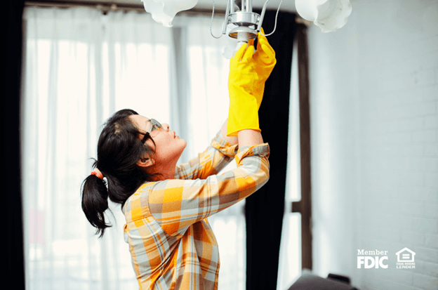 a woman replaces a light fixture in her home during spring renovations