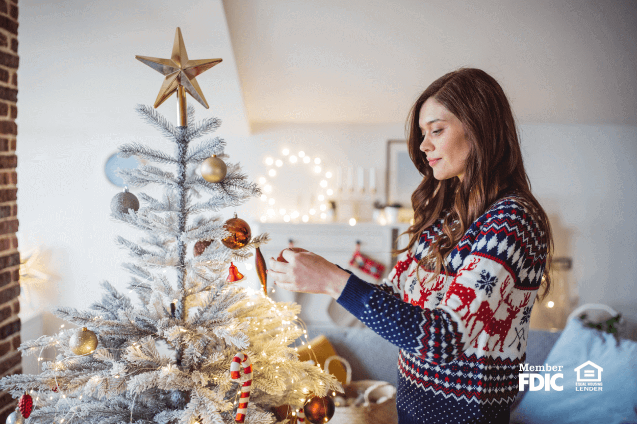 a woman in a holiday sweater decorates her christmas tree