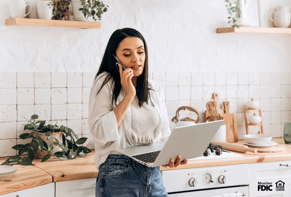 Woman viewing her credit card debt on her computer while using her phone.
