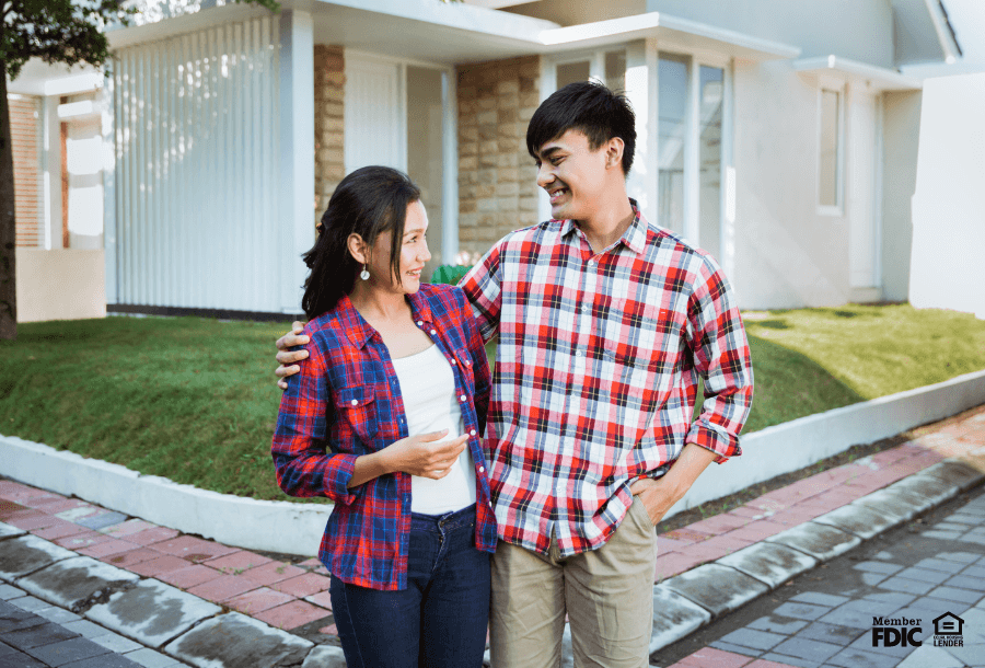 a couple stands in front of their new home