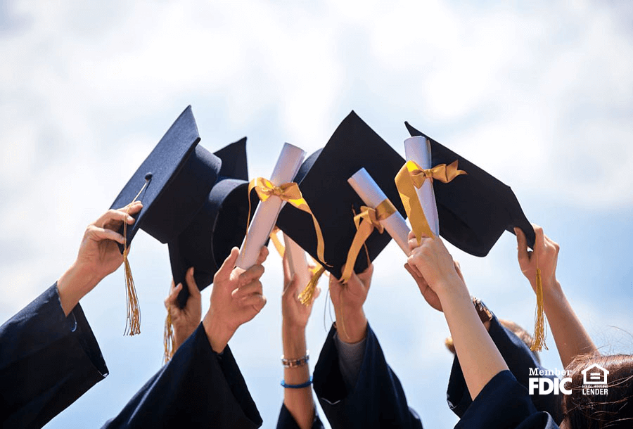 Graduates hold up their mortar boards and diplomas in celebration