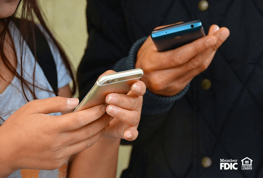 two individuals check their bank accounts using the mobile banking app