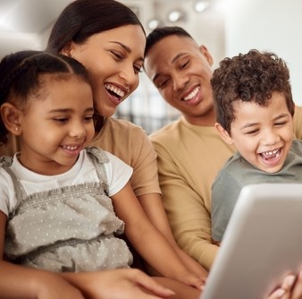 a family laughs together while watching their tablet