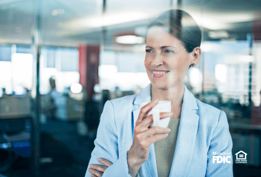 a business woman stares out the window while drinking coffee