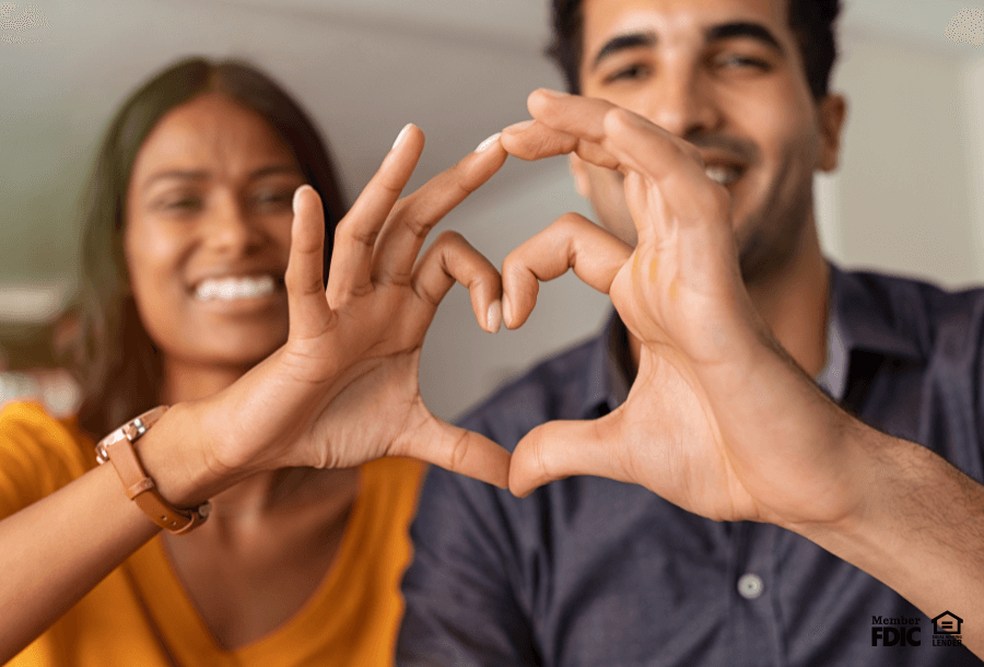 A couple makes a hear out of their fingers