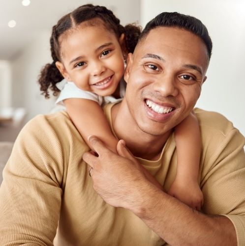 a father and daughter smile at the camera