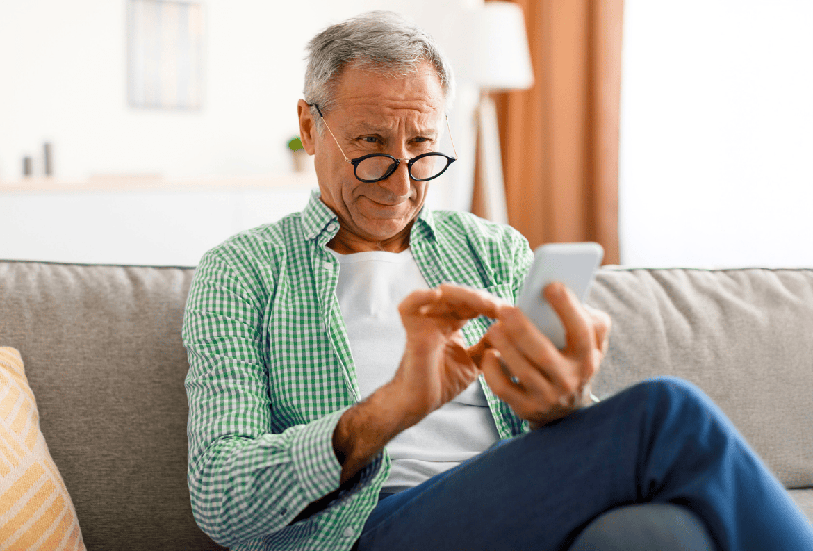 Retirement-aged man struggling with his smartphone and falling for FaceTime fraud.
