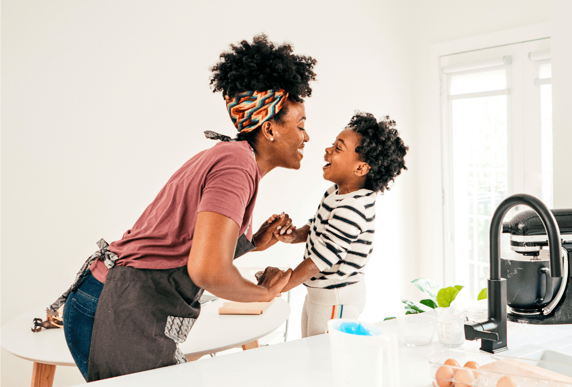 Mother and son laughing in the kitchen while their family money market account earns interest.