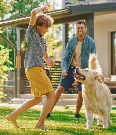 a father and son play with their dog in the backyard