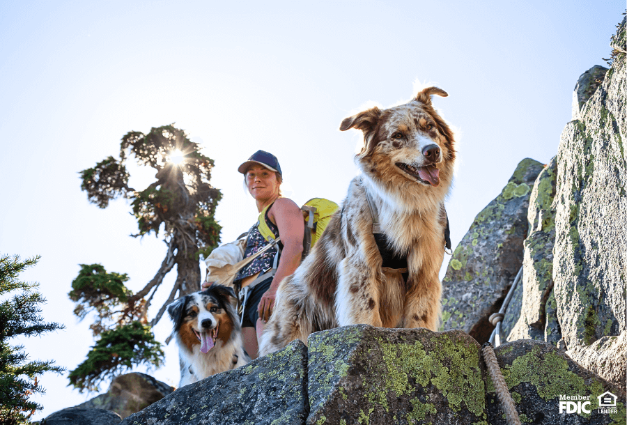 a woman goes hiking with her two fluffy dogs