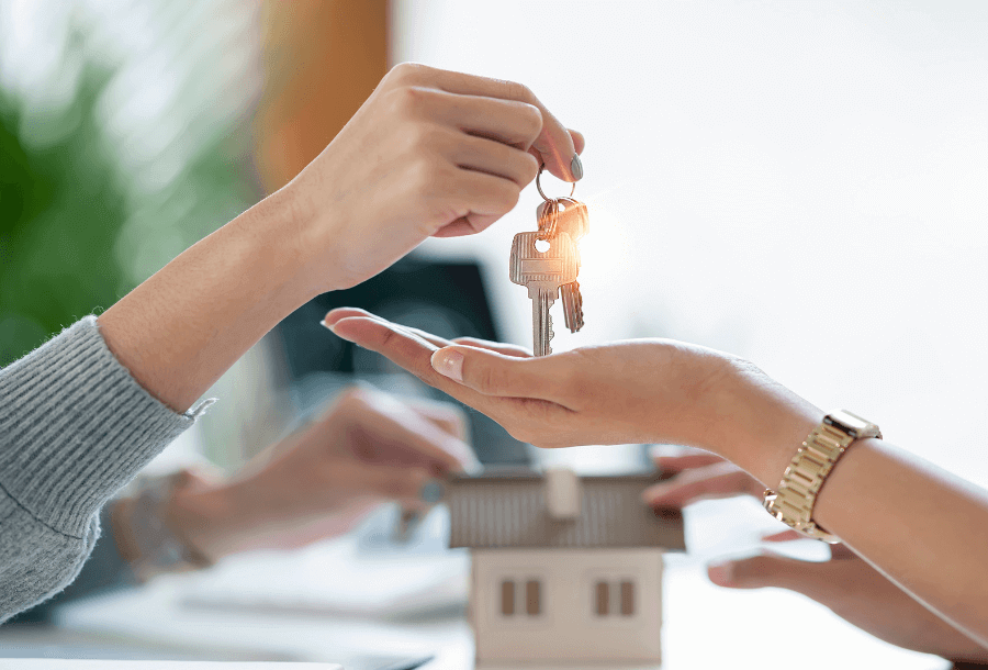 a loan officer hands a homeowner the keys to their new home