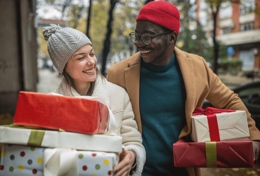 a man and a woman walking outside in the cold with gifts