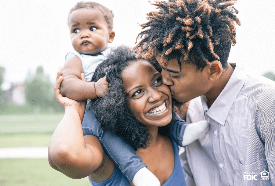 a young couple snuggles together for a family photo