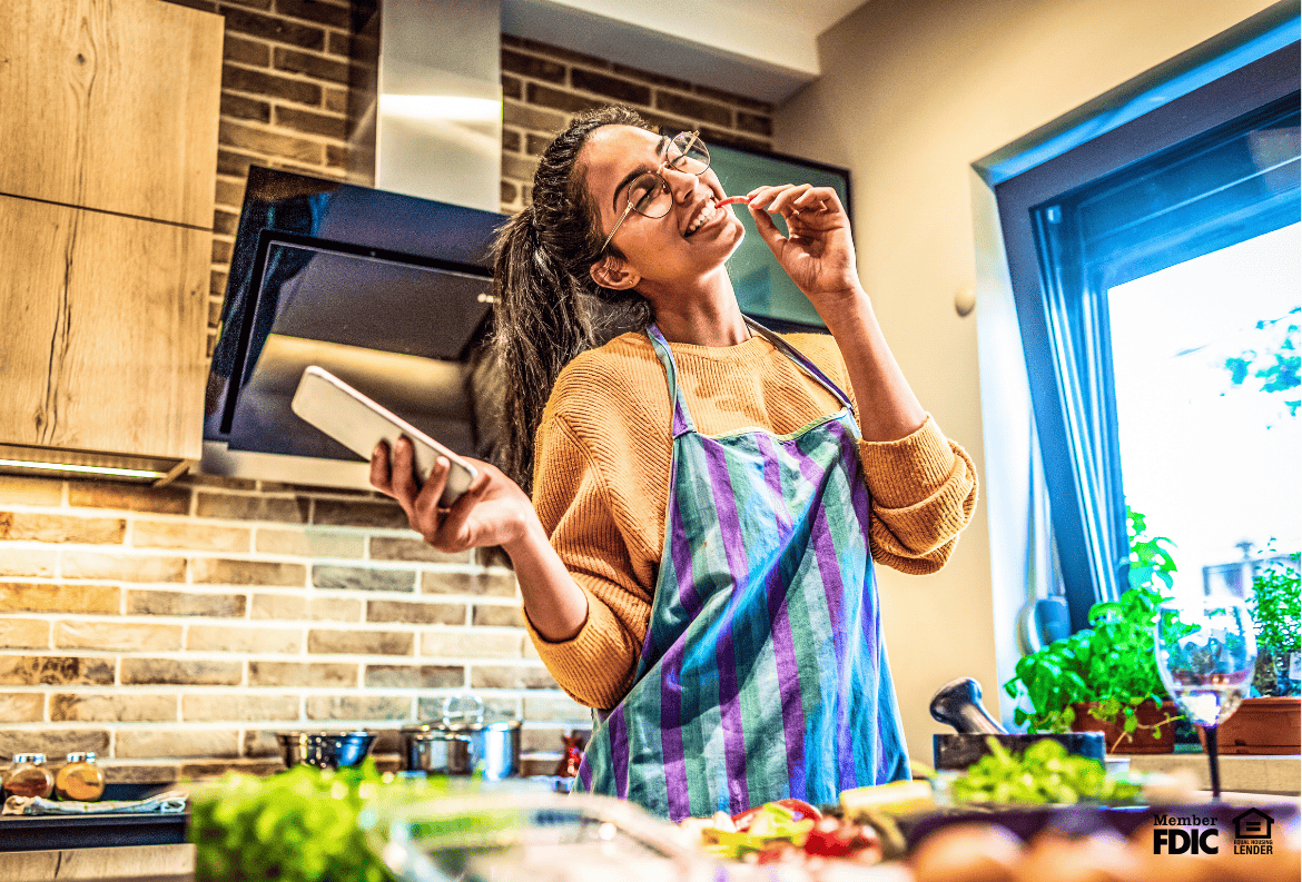 Carefree woman cooks in her kitchen, feeling secure with fixed interest rates in savings and mortgage.
