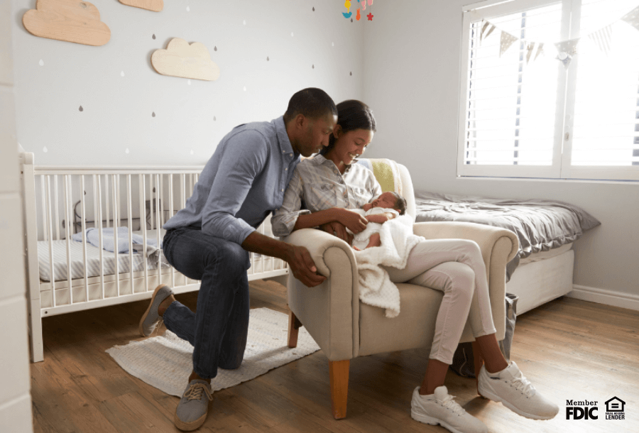 a couple cuddles their new baby in their nursery