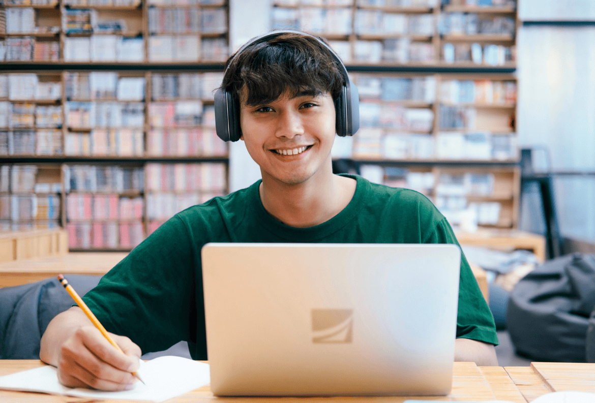 Male college student in the library, feeling confident about his student checking and student savings accounts.