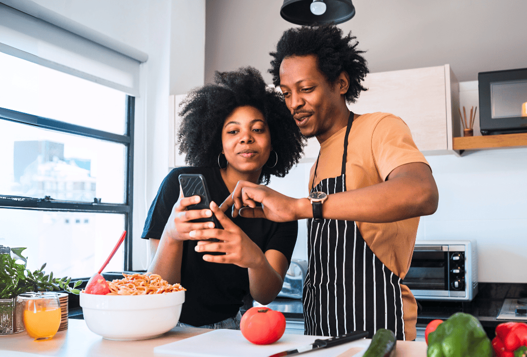 Two people in the kitchen looking up their money market interest earnings for tax season.