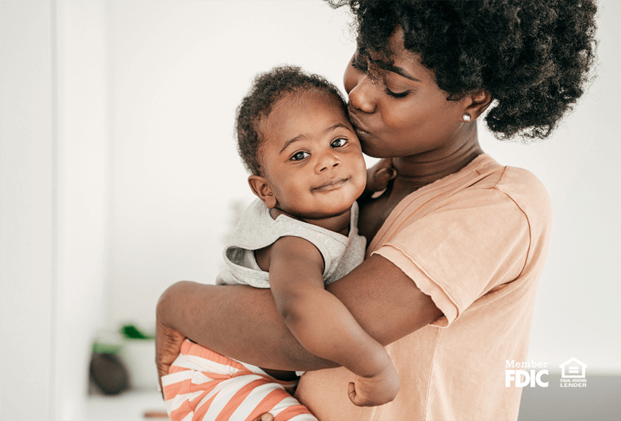 a woman cradles a sweet baby in the new home she purchased with a fixed interest mortgage loan.